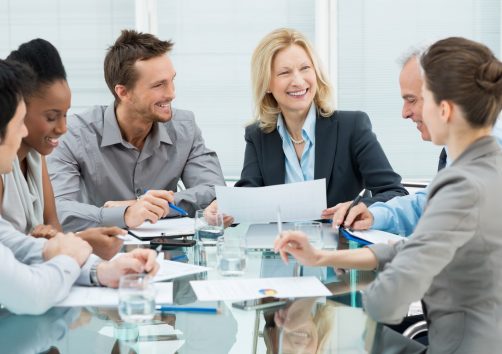 Group Of Happy Coworkers Discussing In Conference Room